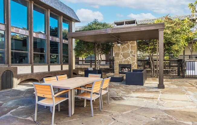 A patio with a table and chairs and a fireplace.