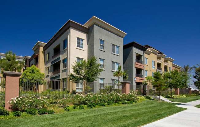 A row of modern apartment buildings with a well-maintained lawn in front. at The Kitt at Warner Center Apartments, California