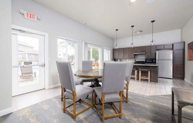 A kitchen with a dining table and chairs in the foreground and an exit sign on the wall.