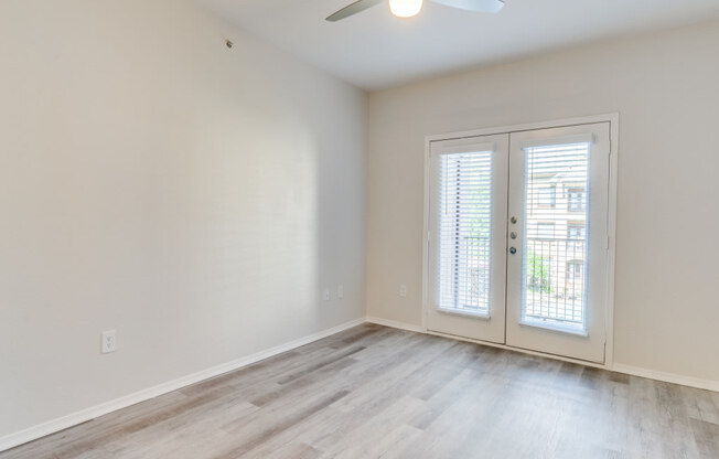 an empty room with a ceiling fan and french doors at Arioso apartments located at 3030 Claremont Dr in Grand Prairie, TX