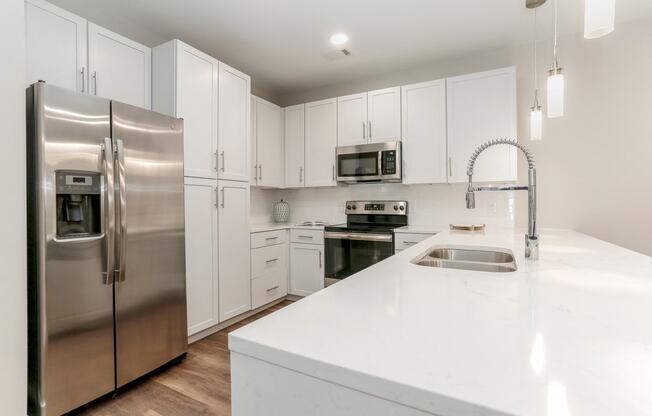 a white kitchen with stainless steel appliances and white counter tops