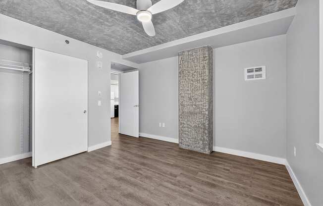 A room with a ceiling fan and a column in the middle.