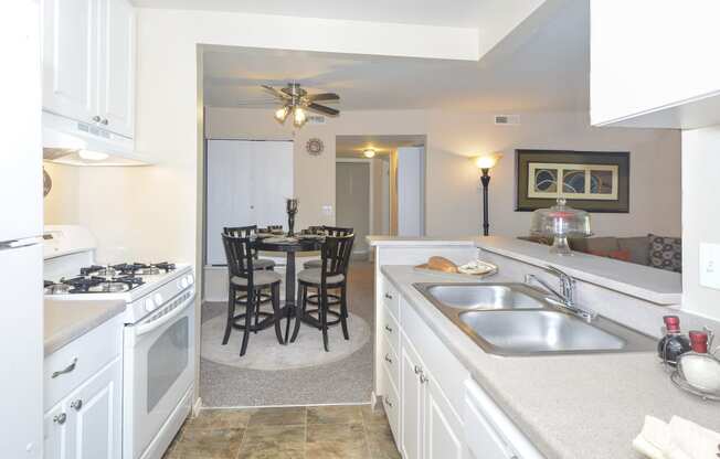 a kitchen with white cabinets and a sink and a table with chairs