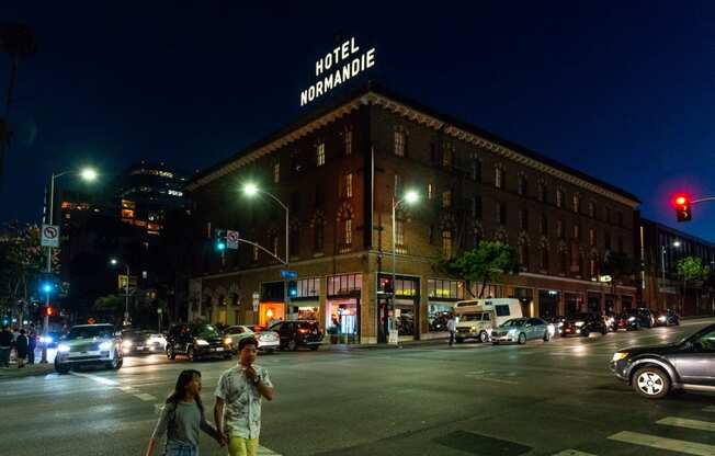 a couple crossing the street in front of a hotel at night