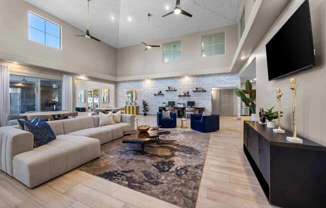 A spacious living room with a large sectional sofa, a coffee table, and a flat-screen TV mounted on the wall.