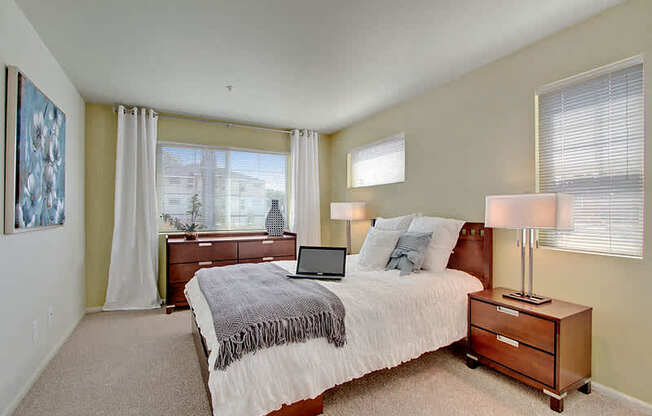 A bedroom with a bed, nightstand, and a painting on the wall. at Mill Creek Meadows Apartments, Mill Creek, WA, 98012