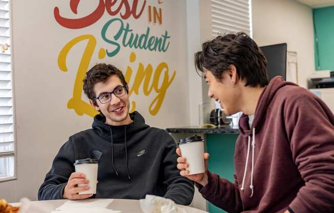 two students sitting at a table in front of a sign that says best in student living