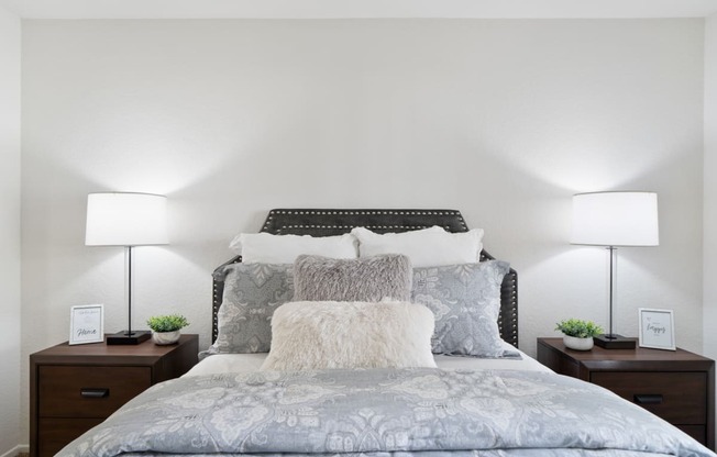 a bedroom with a large bed with pillows and two lamps