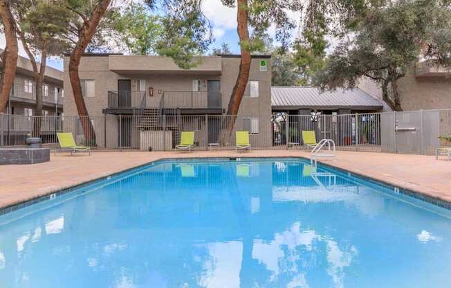 A swimming pool in front of a building surrounded by trees.