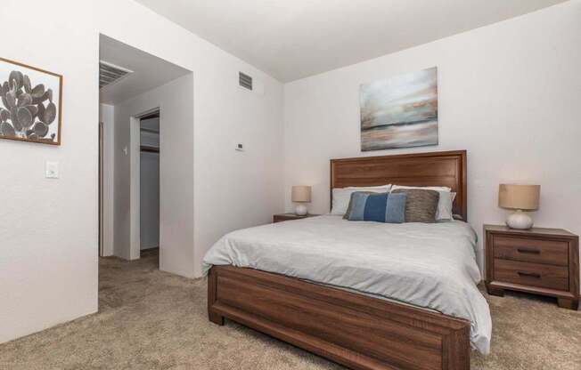 A bedroom with a bed, nightstands, and a painting on the wall.