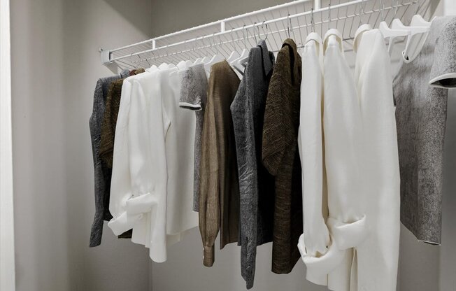 a wardrobe with white clothes and a white hanger