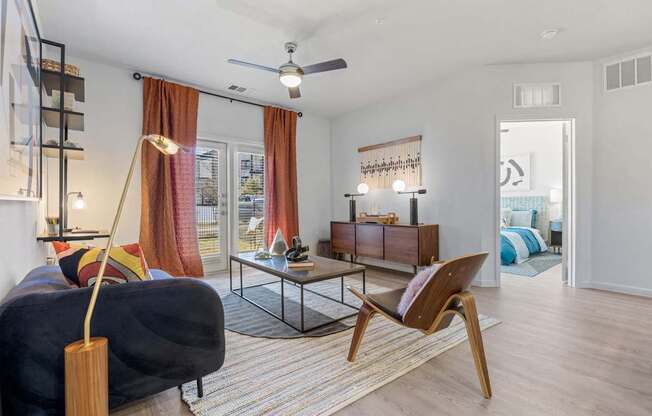 A living room with a black couch, a wooden chair, and a glass table. at Bridge at Tech Crossing, Austin