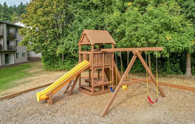 a wooden swing set with a yellow slide in a backyard  at Sitka Heights, Washington, 98424