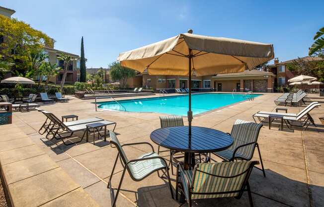 a swimming pool with tables and an umbrella