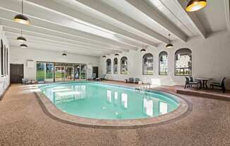 A large indoor swimming pool with a brown floor and white walls.