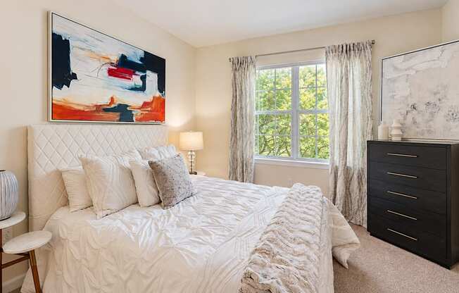 Bedroom with white bedding, a quilted headboard, and a black dresser beside the window at Elevation 3505 in Atlanta, GA.