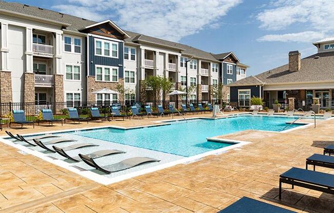 a swimming pool with lounge chairs in front of an apartment building at Promenade at Newnan Crossing, Newnan, GA 30265