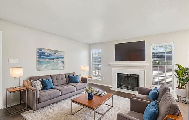 A living room with a grey couch, a coffee table, a fireplace, and a painting on the wall.