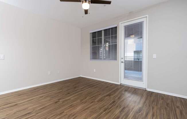 A room with a ceiling fan and wooden flooring.