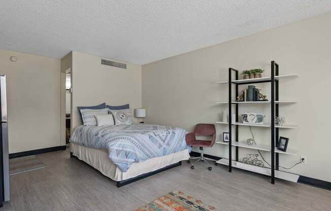 A bedroom with a bed, chair, and shelves.