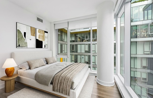 A bedroom with a large bed and a lamp on a side table.