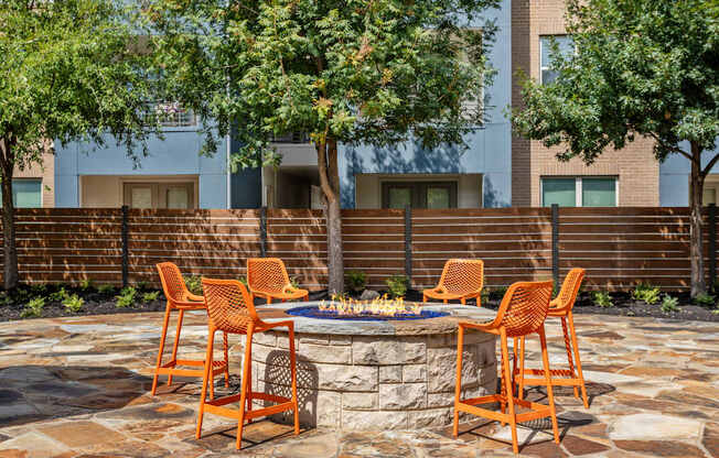 A patio with a fire pit and chairs.