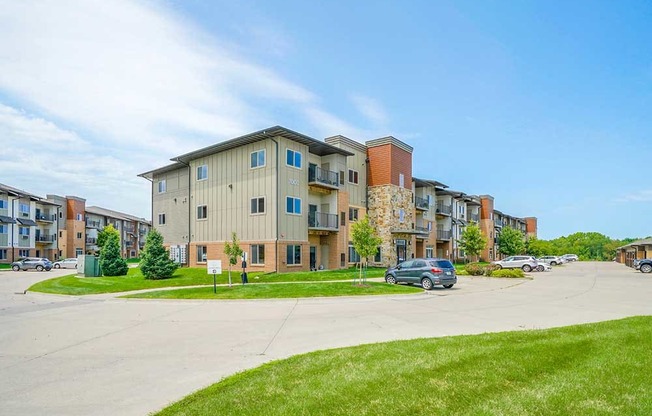 A brick and stone apartment building with professionally landscaped lawns surrounding it.