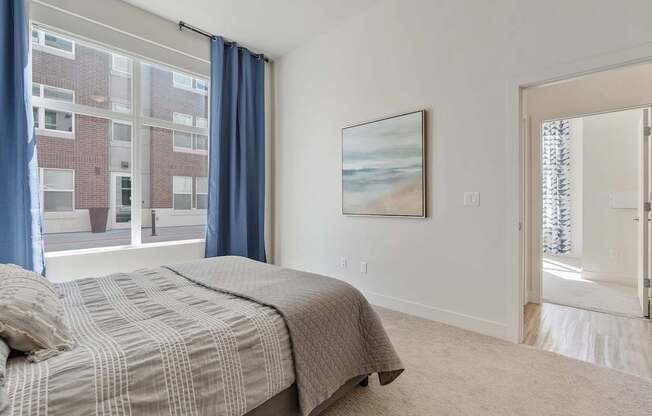 a bedroom with a bed and a large window with blue curtains