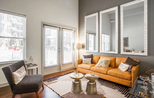 A living room with a couch, chair, and mirrors.