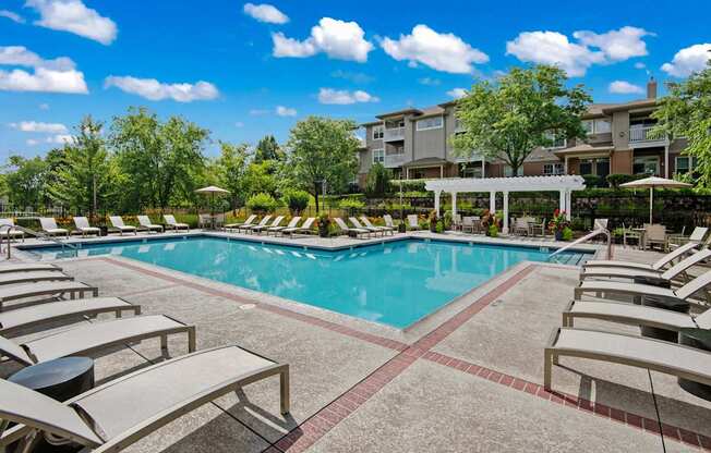 A large swimming pool surrounded by sun loungers and umbrellas.