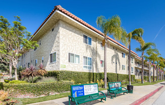 a building with palm trees and benches in front of it