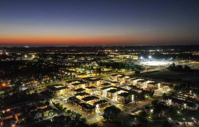 an aerial view of Sierra Gateway Apartments at night with Sierra College in the distance with the stadium lights lit up.