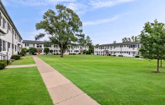 the view of a grassy yard between two apartment buildings