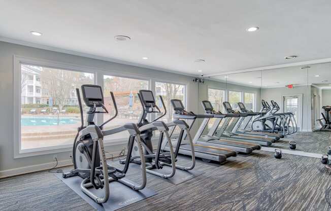 a row of treadmills and exercise machines in a fitness room