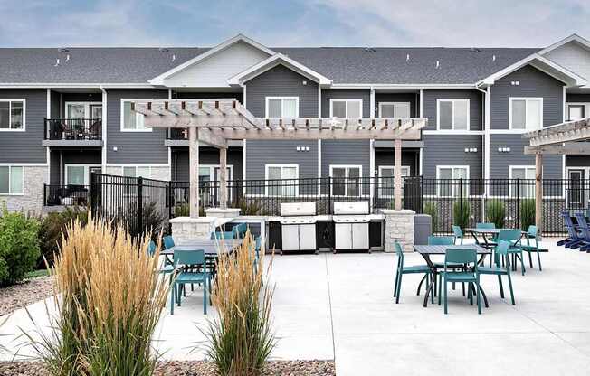 A patio area with tables and chairs in front of apartment buildings.