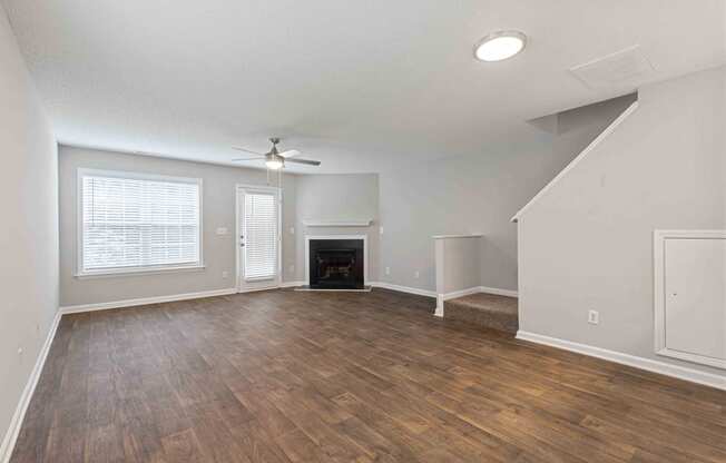 an empty living room with a ceiling fan and a fireplace