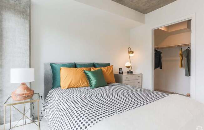 A bedroom with a bed, a lamp, and a dresser.