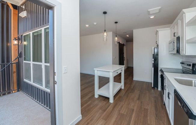 a renovated kitchen and living room with a large window and a white table at The Crossings at Windsong, Prescott Valley, Arizona