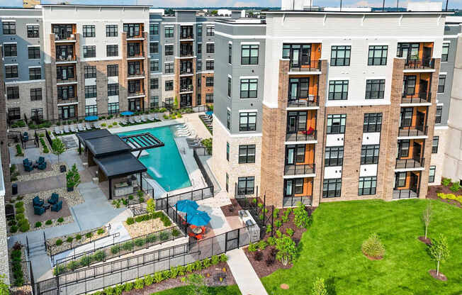 Apartment complex with a pool and a green lawn.