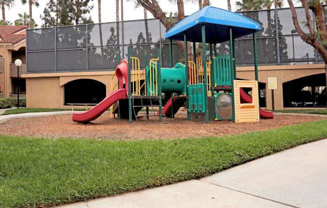 A playground with a red slide and a blue canopy.