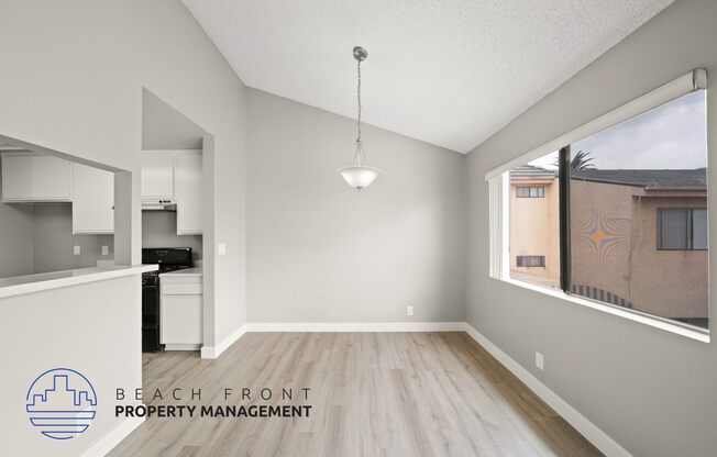 an empty living room and kitchen with wood flooring and a window