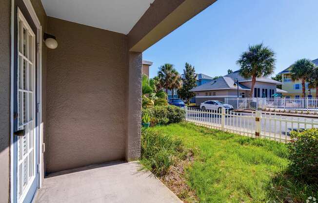 A view of a house's front porch with a white door and a concrete floor.