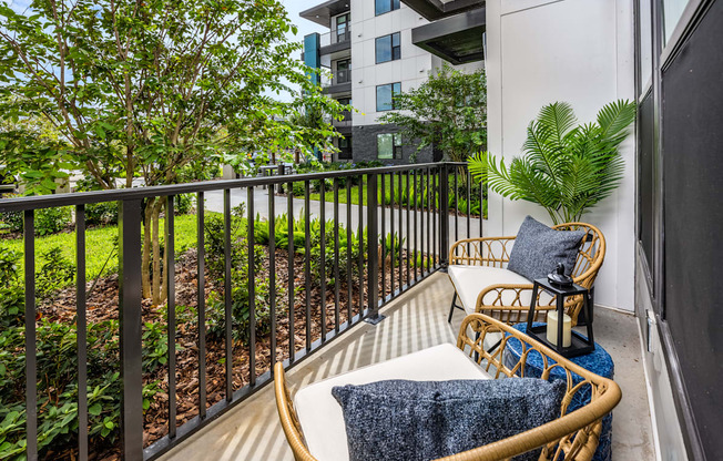 a balcony with two chairs and a table and some plants at The Alibi at Lake Lilly, Ocoee, FL