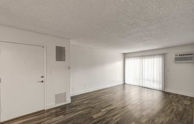 an empty living room with wood flooring and a window