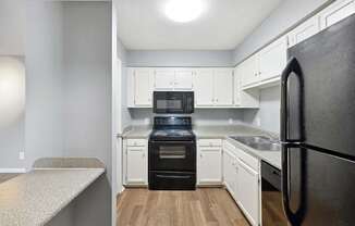 A kitchen with a black refrigerator and white cabinets  at Governors House, Huntsville, 35805