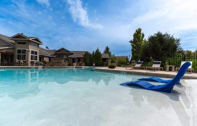 a large swimming pool with a blue chair in front of a building