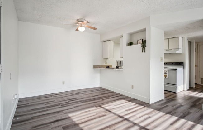 an empty living room and kitchen with a ceiling fan