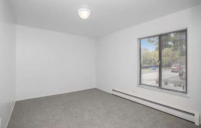 an empty bedroom with a large window at Fairlane Apartments in Springfield, MI
