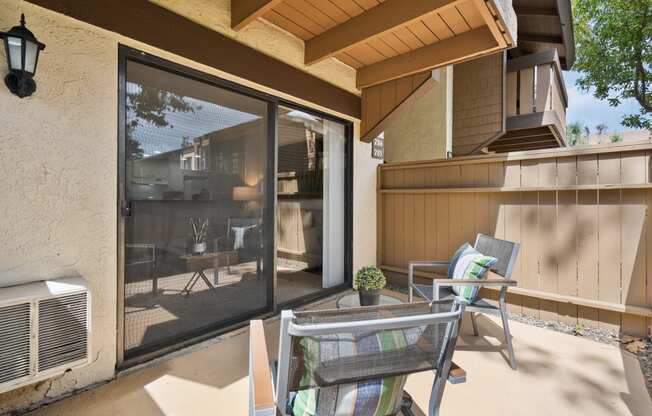 a patio with two chairs and a table and a sliding glass door