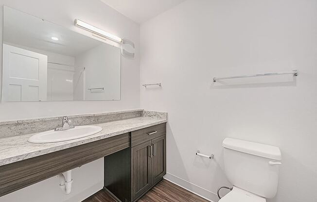 A white toilet sits in a bathroom next to a sink and mirror.
